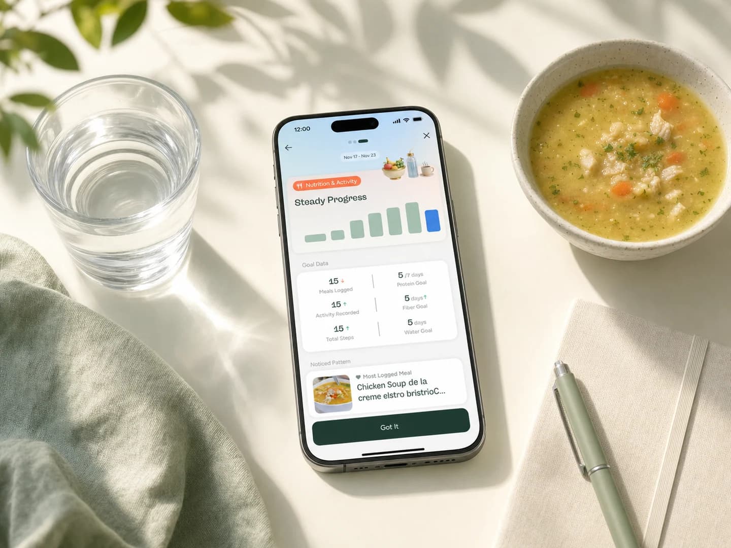 Phone showing a Glowise weekly nutrition insight beside soup, water, and a journal