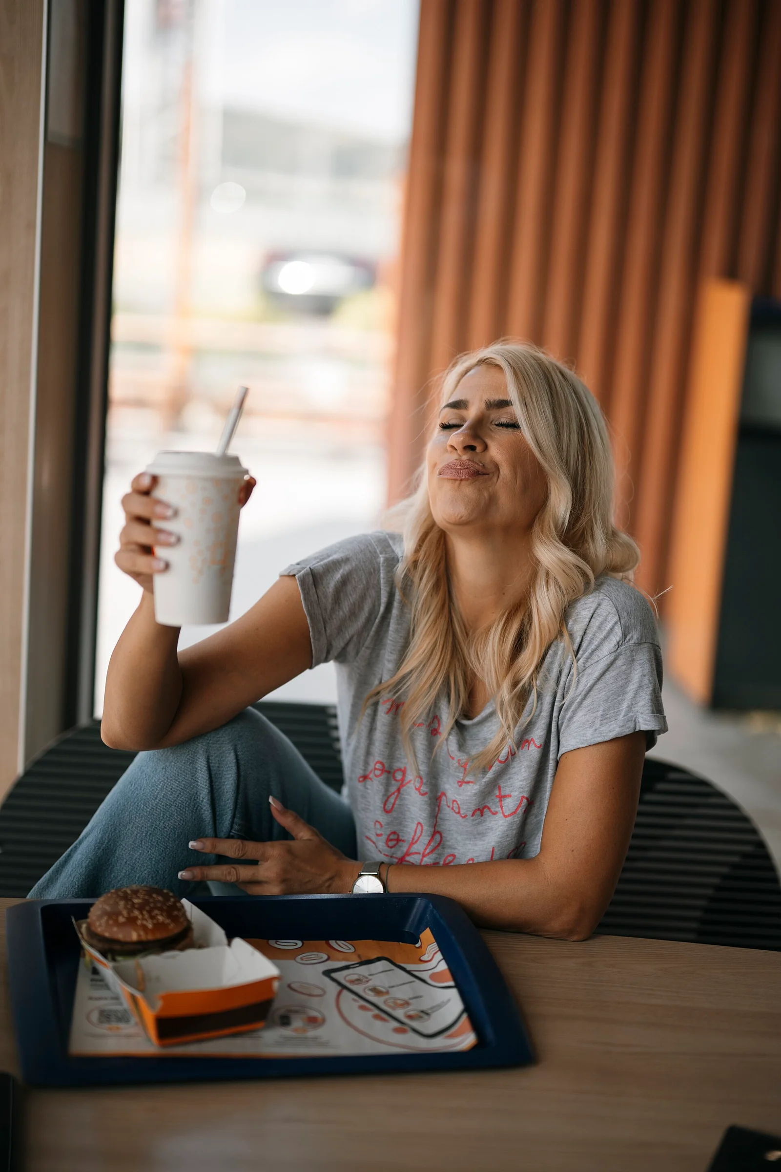 Woman seated by a window holding a cup at a table