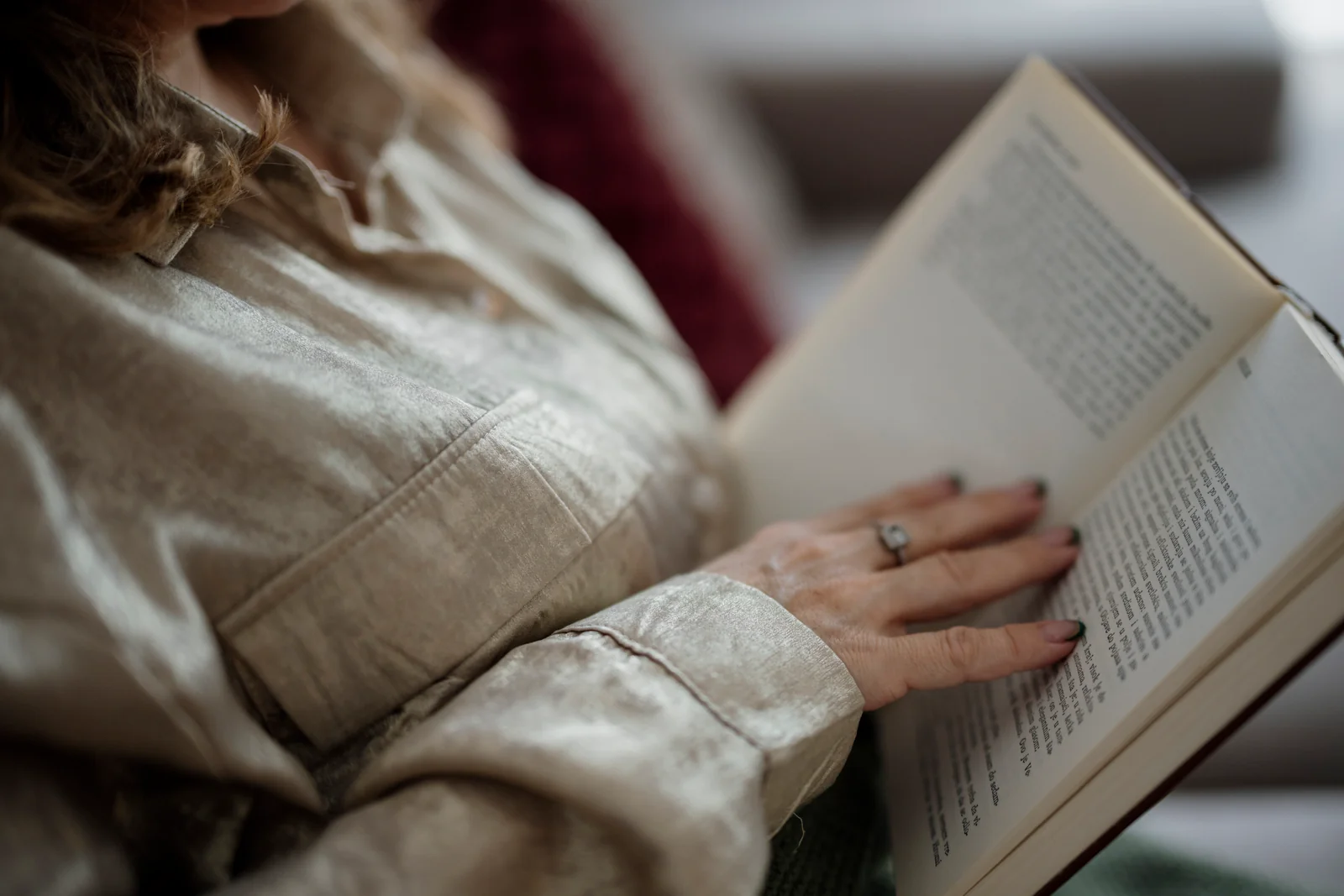 An adult resting indoors while reading a book